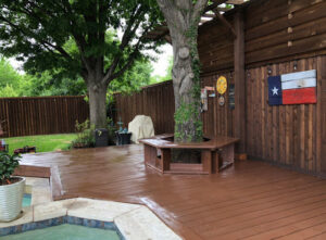 A backyard featuring a pool, deck, and a well-maintained stained wood fence by Texas Tuff Stain and Seal in Fort Worth, TX.