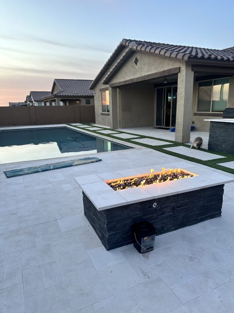 A newly completed backyard featuring a modern swimming pool and a cozy fire pit, designed by All Valley Pools in Avondale, AZ.