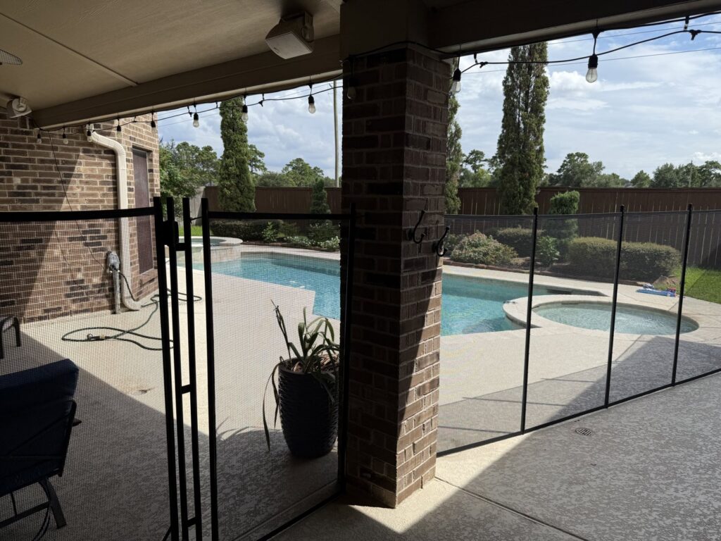 A backyard swimming pool secured with a black mesh safety barrier by Lone Star Pool Fence in Houston, TX.