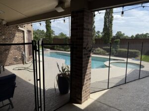 A backyard swimming pool secured with a black mesh safety barrier by Lone Star Pool Fence in Houston, TX.
