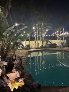 A backyard pool area illuminated with decorative string lights and landscape lighting, installed by GL3 Luxury Lighting in Anaheim, CA.