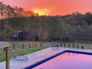 A beautiful backyard pool reflecting a vibrant sunset, installed by Luxury Outdoors in Murfreesboro, TN.