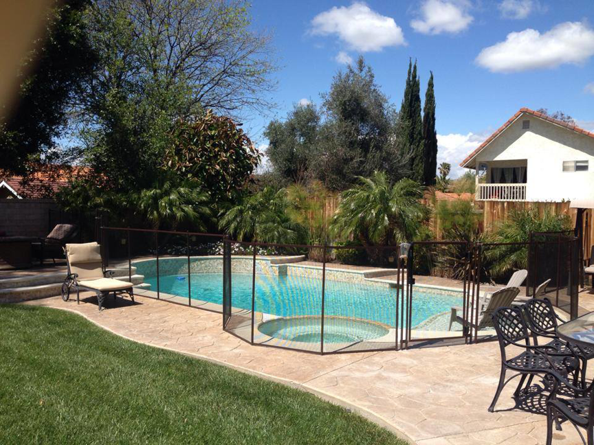 A beautiful backyard pool secured with a black mesh safety fence by Baby Guard Pool Fence Los Angeles, CA