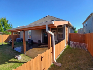 A backyard with a wooden privacy fence and patio cover installed by Olson Handyman Services, LLC in New Braunfels, TX
