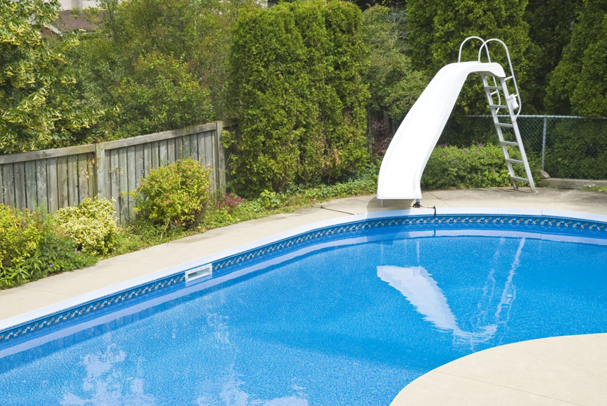 A beautiful backyard swimming pool with a white slide installed by Midwest Custom Pools, LLC in Lawrence, KS.