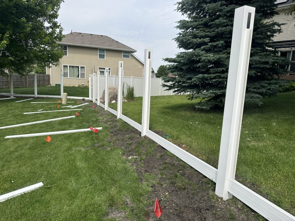 Backyard vinyl fence installation with posts and rails laid out, a project by Top Rail Fence Des Moines in West Des Moines, IA.