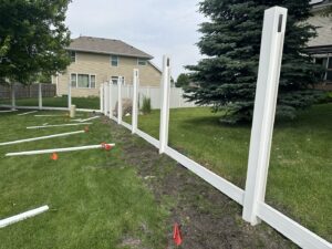Backyard vinyl fence installation with posts and rails laid out, a project by Top Rail Fence Des Moines in West Des Moines, IA.