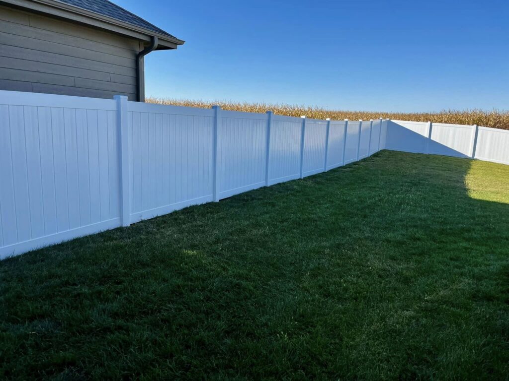 A long white vinyl fence installed in a residential backyard by Custom Vinyl Fabrication in Omaha, NE.