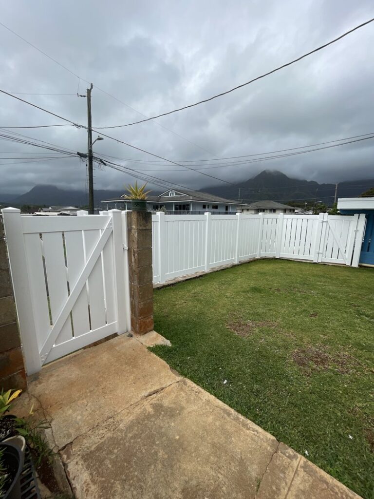A white vinyl fence with a gate installed in a residential backyard by Redmond Valleywide - Hawaii's Fence Company in Kapolei, HI