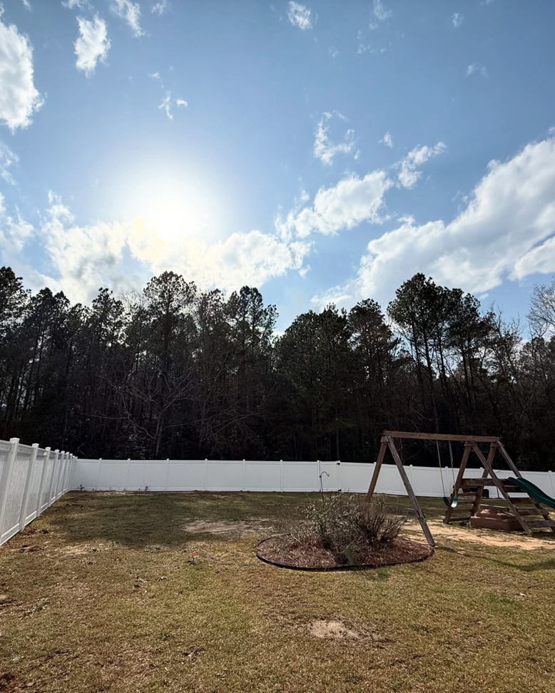 A spacious backyard featuring a new white vinyl fence installed by Brock Brothers Fence in Mobile, AL.