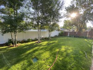 A white vinyl privacy fence installed in a residential backyard with mature trees by Rio Fence Co. in Lincoln, NE.