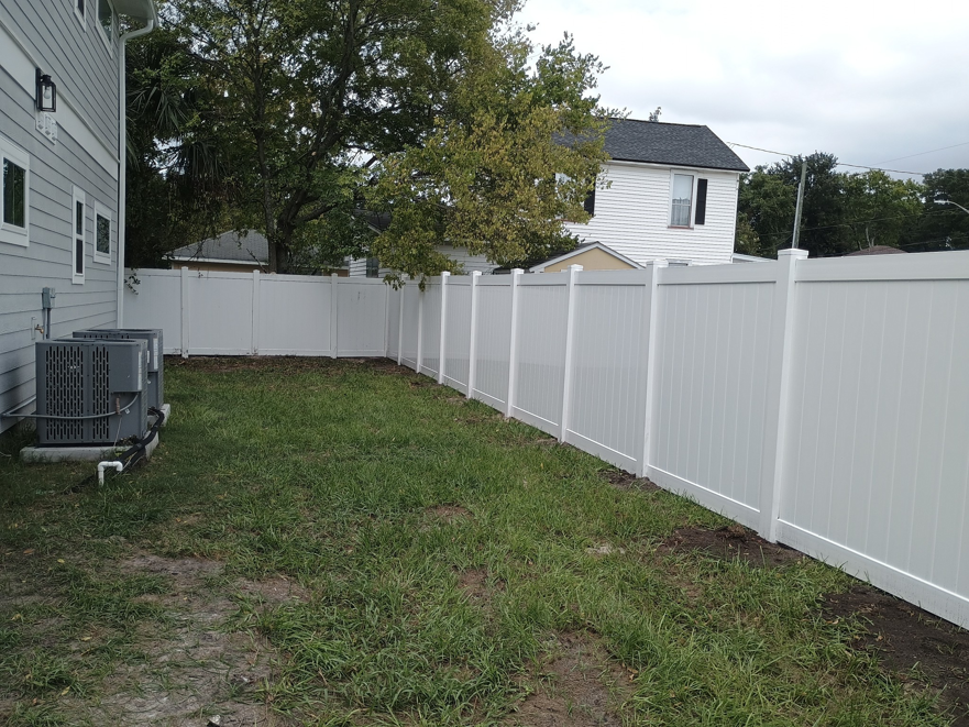 A long white vinyl privacy fence installed in a residential backyard by Geo's Custom Fencing, LLC in Jacksonville, FL.