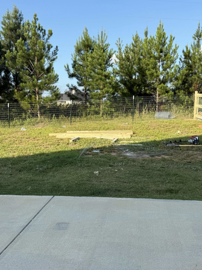 A backyard with a newly installed wire fence and lumber materials, indicating a fencing project by G2 Home Solutions in Phenix City, AL.
