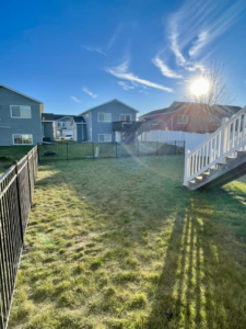 A residential backyard featuring a newly installed black ornamental fence and a white vinyl fence in the background by VASE Construction, LLC in Fargo, ND.