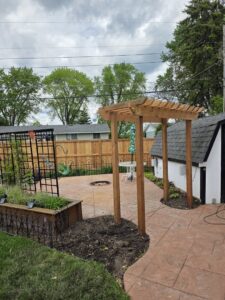 A backyard featuring a newly installed wood fence and a wooden pergola by MN Mike's Fence and Repair in Lakeville, MN.
