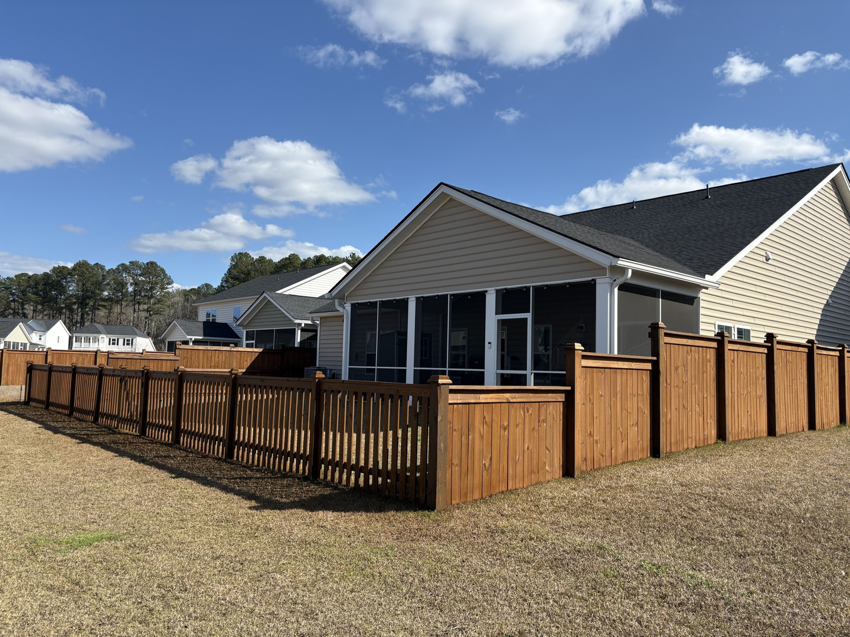 A wide view of a residential backyard featuring a complete wood fence enclosure installed by Stain and Go in Summerville, SC.