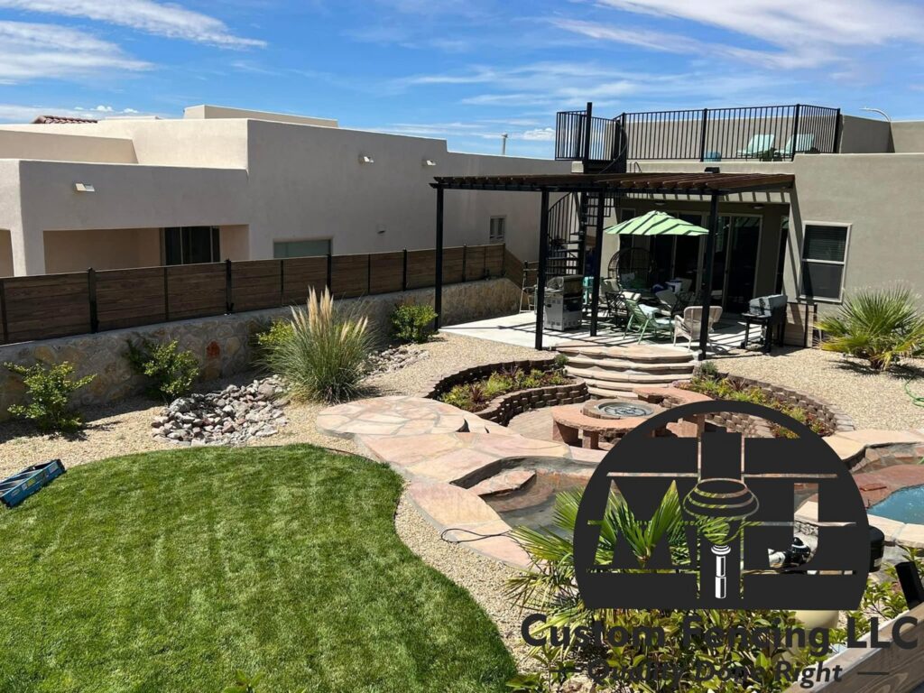 A beautiful backyard featuring a newly installed wood fence on a stone wall, a pergola, and a fire pit by MJ Custom Fencing in Las Cruces, NM.