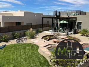 A beautiful backyard featuring a newly installed wood fence on a stone wall, a pergola, and a fire pit by MJ Custom Fencing in Las Cruces, NM.