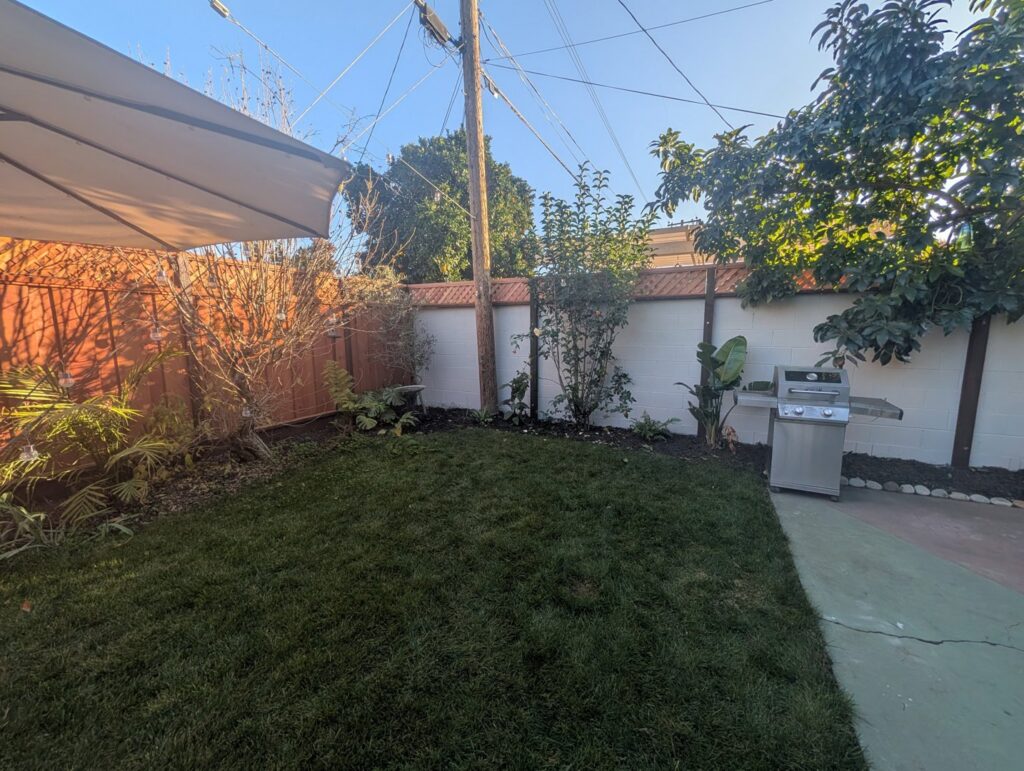A backyard featuring a wooden fence and a white block wall with wooden posts, installed by Superior Fence & Rail in San Jose, CA.
