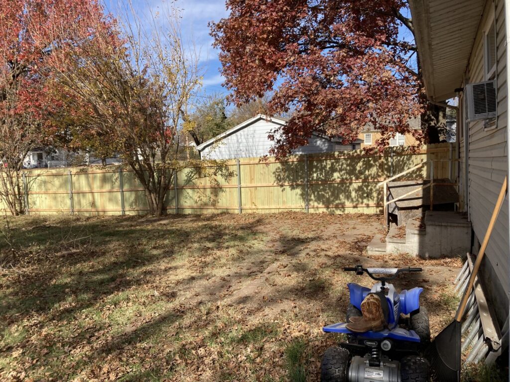 A long wooden privacy fence enclosing a residential backyard, installed by 12 Corners Fence Company in Tecumseh, OK