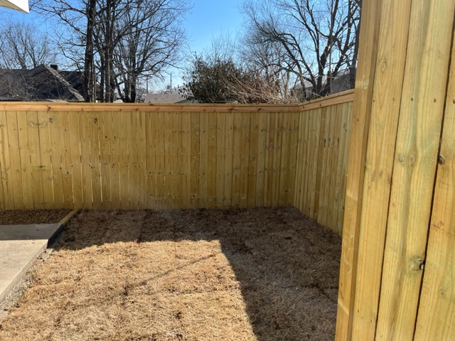 A newly installed wood privacy fence corner in a backyard by Fence Solutions of NWA in Gravette, AR.