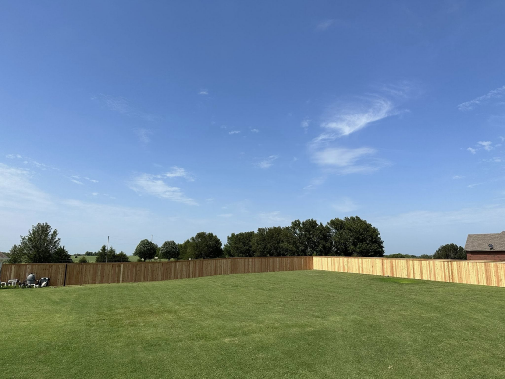 A wide view of a backyard featuring a new wood privacy fence installed by DB Construction in Fort Smith, AR.