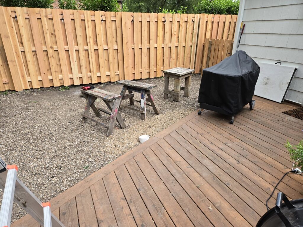 A newly installed wood privacy fence in a backyard with a deck and grill by Pride Fence in Peabody, MA.