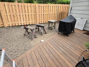 A newly installed wood privacy fence in a backyard with a deck and grill by Pride Fence in Peabody, MA.