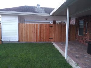 A newly installed wood privacy fence with a double gate, viewed from a backyard patio, by Country Boyz fencing in Biloxi, MS.
