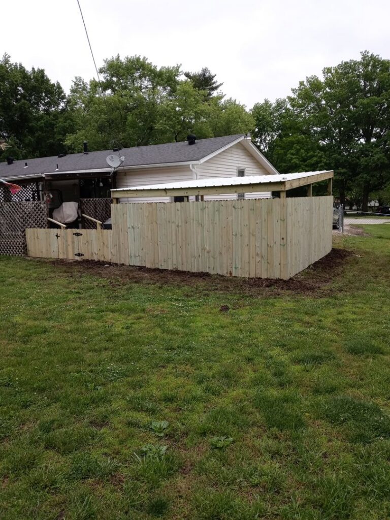 A newly installed wood privacy fence with a gate in a backyard by Lujan Fencing in Independence, MO.