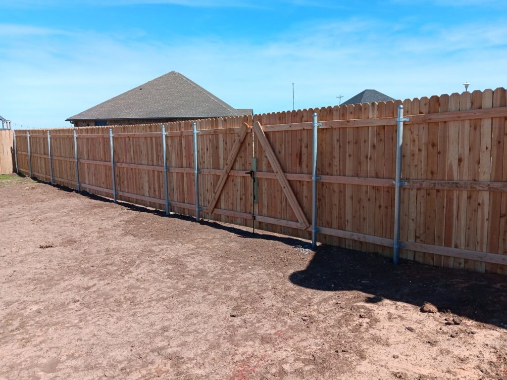 A backyard wood privacy fence with a gate installed by Veteran Fence Company LLC in Shawnee, OK.