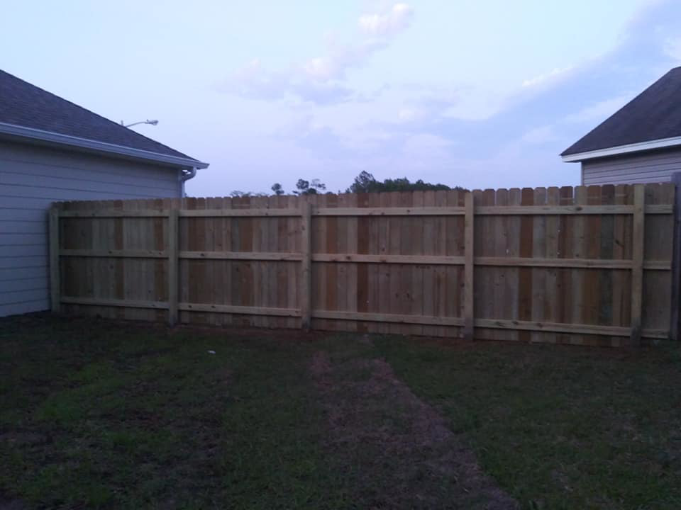 A long section of a newly installed wood privacy fence in a residential backyard by Country Boyz fencing in Biloxi, MS.