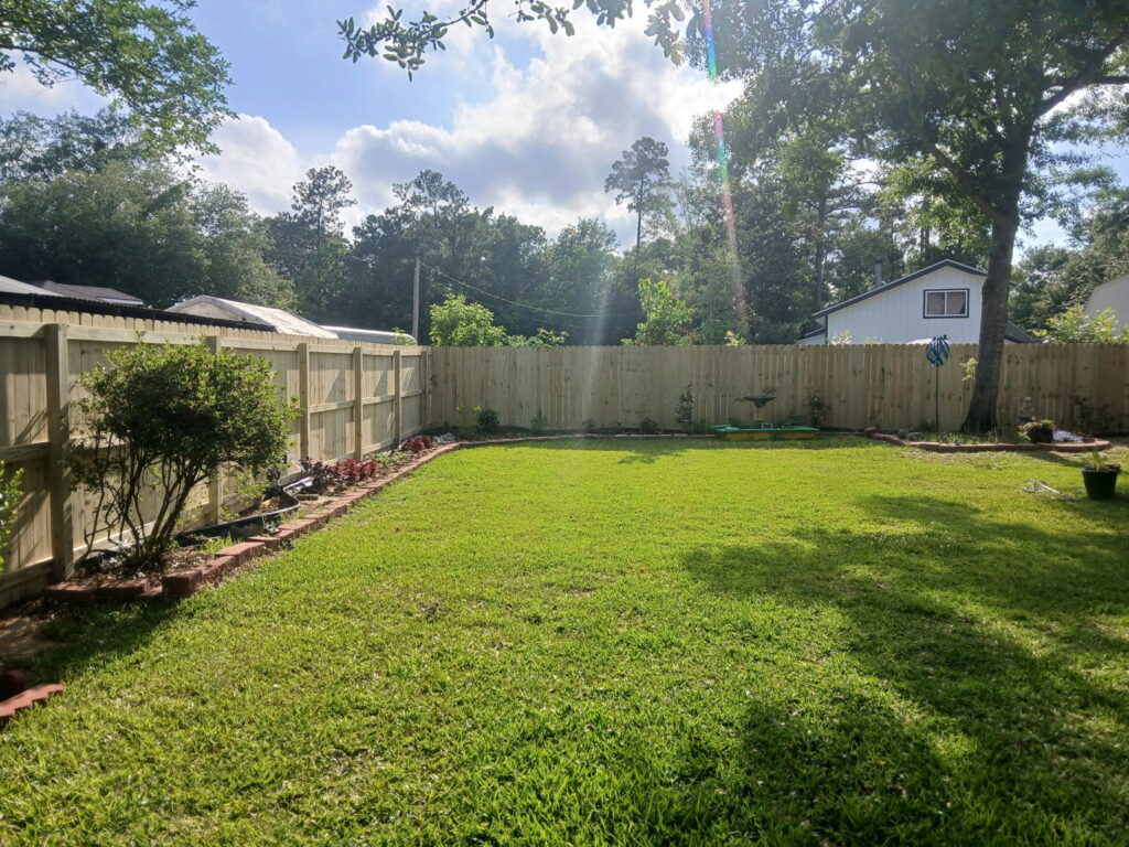 A newly installed wood privacy fence lining a backyard by FenceCo LLC in Pass Christian, MS.