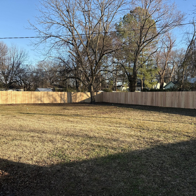 A wide view of a backyard with a new wood privacy fence installed by McDaniel Quality Fencing LLC in Muldrow, OK.