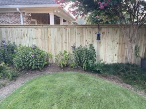 A newly installed wood privacy fence in a landscaped backyard by TC Fencing LLC in Tuscaloosa, AL.