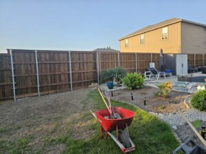 A newly installed wood privacy fence with metal posts in a backyard by Stand Strong Fencing of Plano, TX