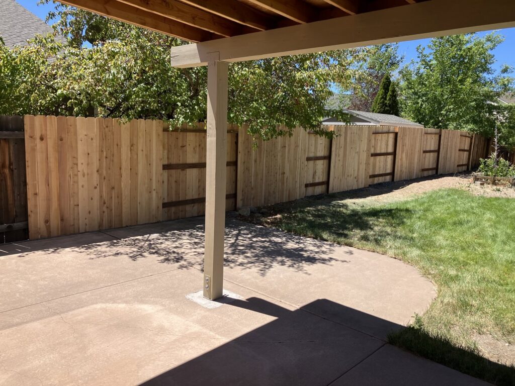 A newly installed wood privacy fence enclosing a backyard patio area by This And That Fence in Reno, NV.