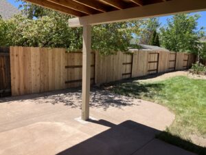 A newly installed wood privacy fence enclosing a backyard patio area by This And That Fence in Reno, NV.