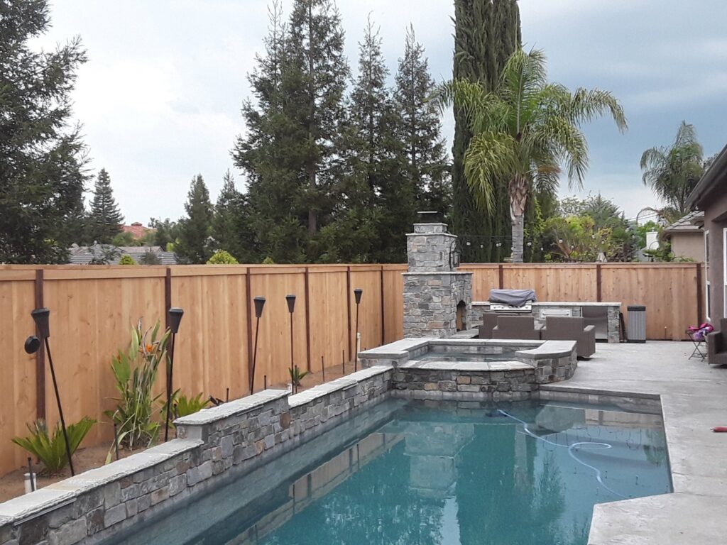 A backyard featuring a new wood privacy fence and a swimming pool, installed by The Fence Company in Fresno, CA.
