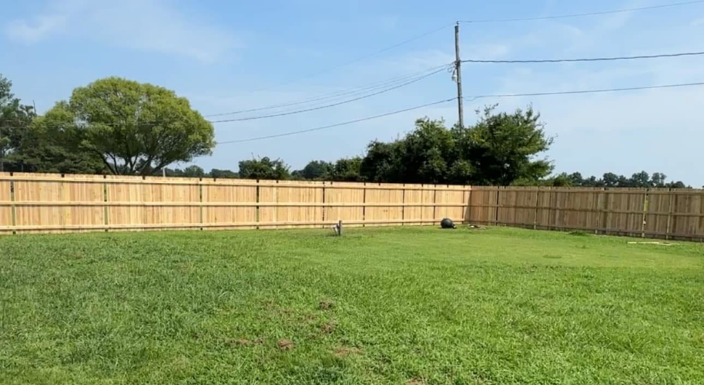 A long, newly installed wood privacy fence enclosing a spacious backyard by Swanson Fencing in Jonesboro, AR.
