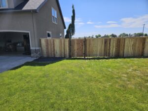 A new wood privacy fence with a gate installed in a residential backyard, showcasing the work of Regan Fencing & Services in Nampa, ID.