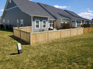 A newly installed wood privacy fence enclosing a backyard, complete with a small gate, by Superior Fence & Rail Richmond, VA.