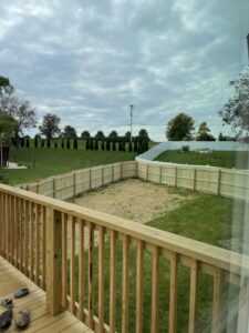 A spacious backyard featuring both wooden privacy fencing and white vinyl fencing in the distance, installed by Roark Fencing in Lexington, KY.