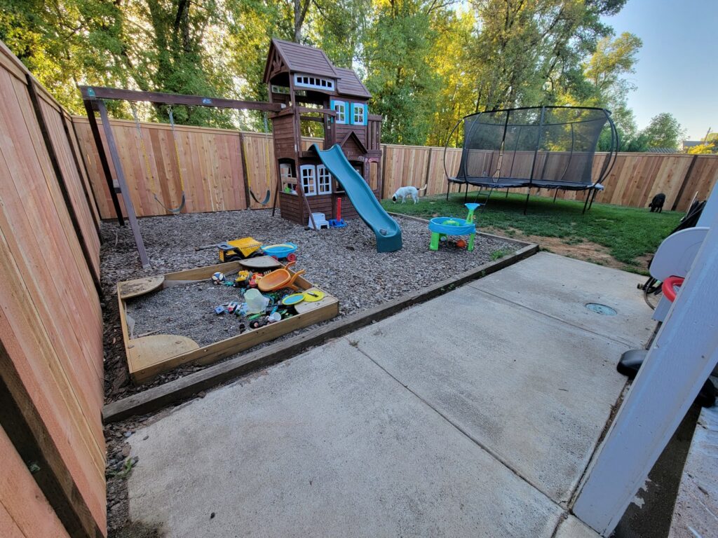 A wooden privacy fence enclosing a backyard play area with a swing set and trampoline, installed by Faxon Fencing in Corvallis, OR.