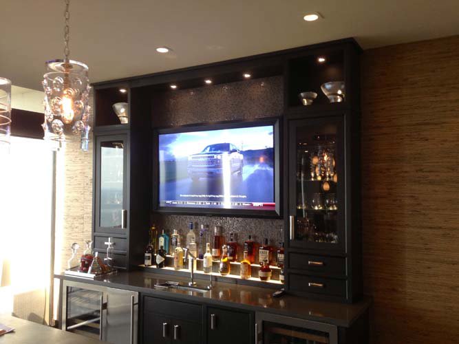 A stylish bar area with under-cabinet lighting and recessed lights installed by Christensen Electric in Galveston, TX.