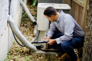 A Barefoot Mosquito & Pest Control technician inspecting an outdoor AC unit and taking notes in Austin, TX.