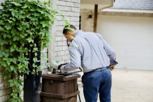 A Barefoot Mosquito & Pest Control technician inspecting a rain barrel for mosquito breeding sites in Austin, TX.