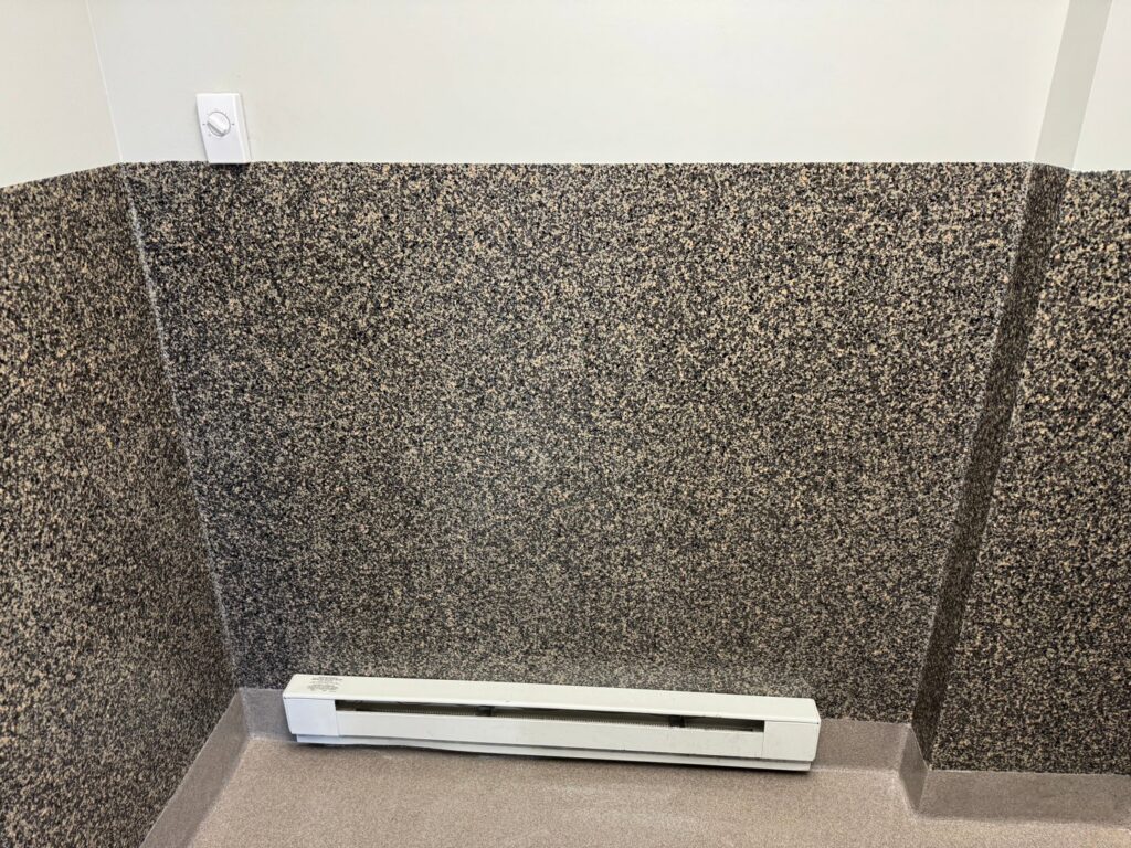 A baseboard heater and wall-mounted thermostat installed in a room by AC-DC Electric in Severance, CO.