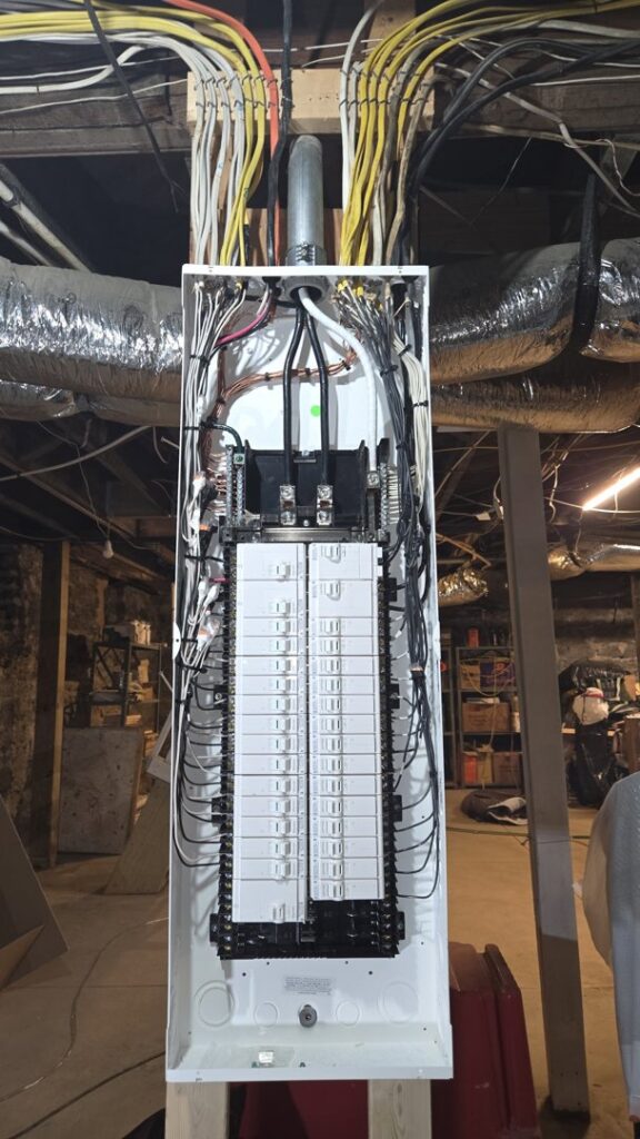A newly installed electrical panel with organized wiring in a basement, completed by Grounded Electric LLC in Smithfield, VA.
