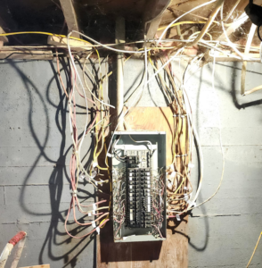 An open electrical panel with extensive wiring in a basement, showcasing electrical services by SEL Electric in Truro, NS.